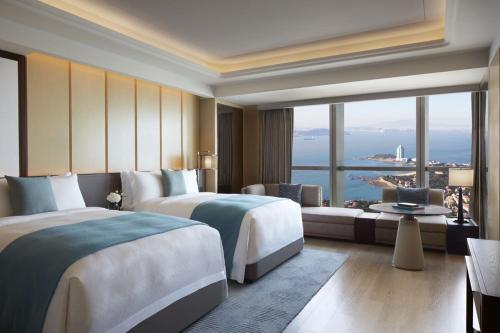 a hotel room with two beds and a large window at The St. Regis Qingdao in Qingdao