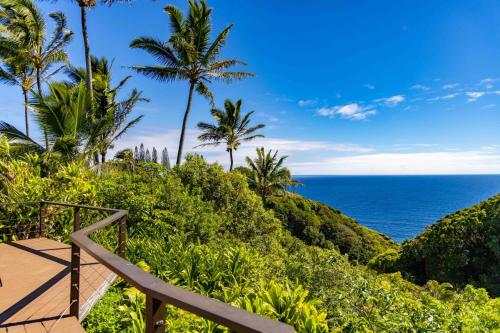 a stairway to the ocean with palm trees at Plumeria Room on a Lush Farm on Maui's North Shore in Huelo