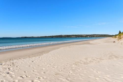 a sandy beach with the ocean in the background at Beachfront Unit - Belle Escapes Jervis Bay in Vincentia