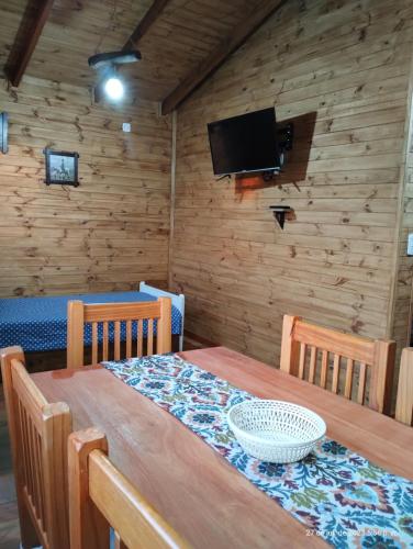 Una mesa de comedor con dos sillas y un televisor. en Cabañas Los Patricios, en Colón