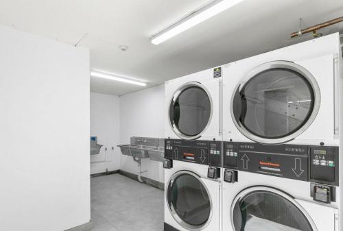 a laundry room with three washing machines in it at Studio Apartment in East Perth in Perth