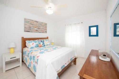 a white bedroom with a bed and a wooden table at Beach Living at Moon Bay with SeaView in Bodden Town