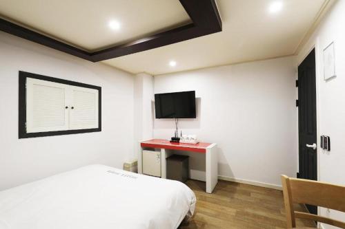 a bedroom with a bed and a desk with a television at Suwon Hotel Praha in Suwon