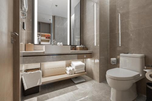 a bathroom with a toilet and a sink and a mirror at The Meixi Lake, Changsha Marriott Executive Apartments in Changsha