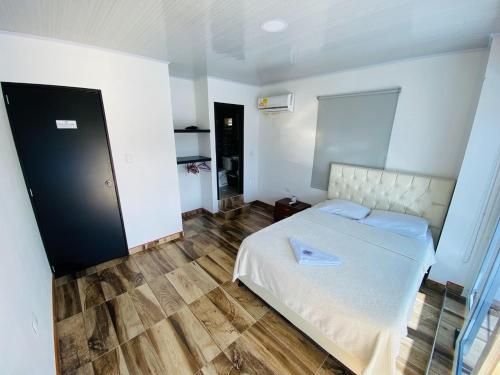Tauramena的住宿－HOTEL LA CASONA，卧室配有白色的床,铺有木地板