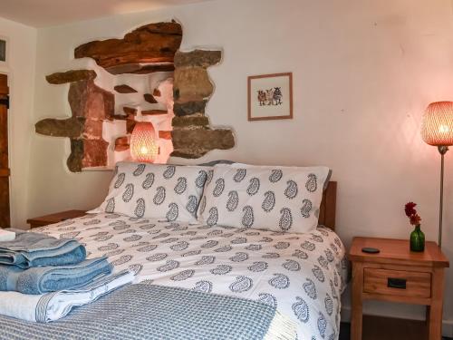 a bedroom with a bed and a stone wall at Greystones in Ravenstonedale
