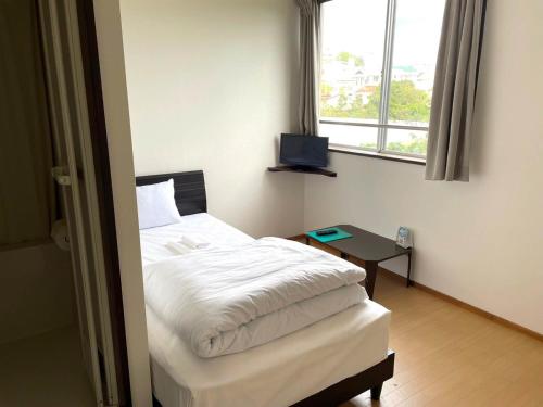 a bedroom with a white bed and a window at Southern Village Okinawa - Vacation STAY 09953v in Kishaba