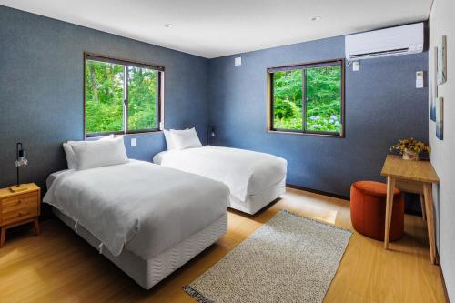 two beds in a room with blue walls and windows at MIZUHO CHALETS by Hakuba Hotel Group in Hakuba