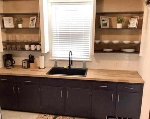 a kitchen with black cabinets and a sink and a window at The House Hotels - Cohasset Lower in Lakewood