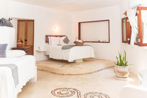 a white bedroom with two beds and a mirror at Casa Takywara in Holbox Island