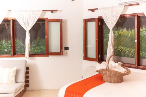 a bedroom with a bed and a chair and windows at Casa Takywara in Holbox Island