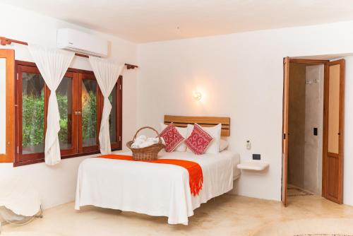 a white bedroom with a bed and windows at Casa Takywara in Holbox Island