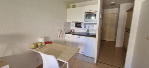 une cuisine avec des armoires blanches et une table en bois dans l'établissement Studio bord de mer à proximité monaco et menton 4 personnes à roquebrune cap martin, à Roquebrune-Cap-Martin