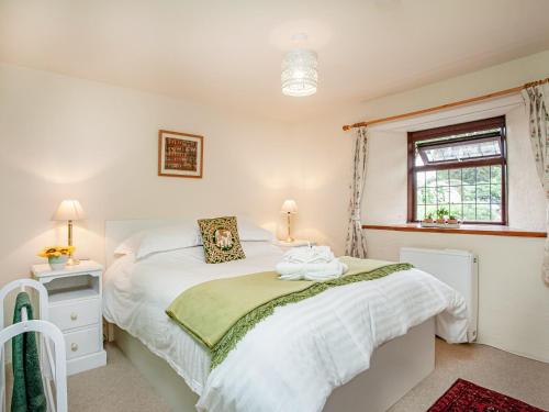 1 dormitorio con cama blanca y ventana en The Nook en Saint Ewe