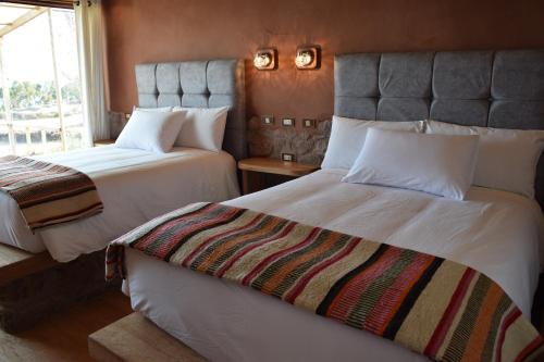 a hotel room with two beds and a window at Allpaluxe Peru Lodge in Ocosuyo