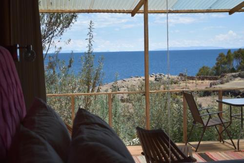 a room with a view of the ocean from a porch at Allpaluxe Peru Lodge in Amantani