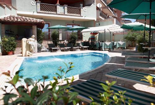 einen Pool mit Stühlen und Sonnenschirmen neben einem Gebäude in der Unterkunft Villa Cristina in Giardini-Naxos