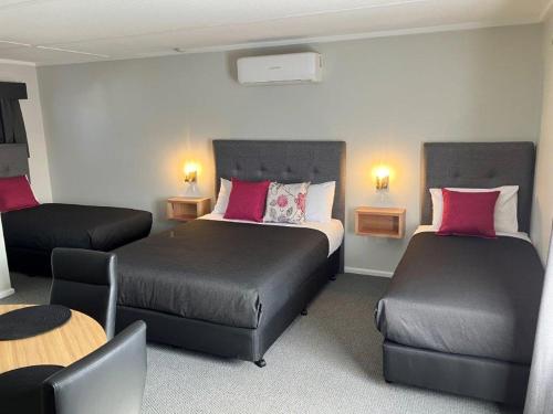 una camera d'albergo con due letti e un tavolo di Deniliquin Motel a Deniliquin