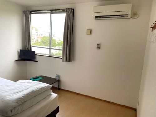 ein Hotelzimmer mit einem Bett und einem Fenster in der Unterkunft Southern Village Okinawa - Vacation STAY 09974v in Kishaba