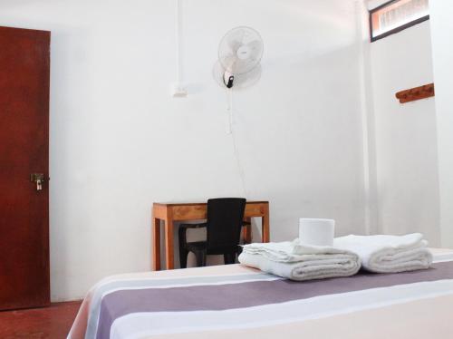 een kamer met een bed, handdoeken en een ventilator bij Casa Albina in Yurimaguas