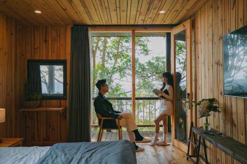 Ein Mann und eine Frau stehen in einem Zimmer mit Fenster in der Unterkunft Lavender Dalat Hotel and Resorts in Da Lat