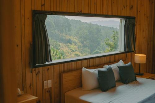 a bedroom with a window and a bed with pillows at Lavender Dalat Hotel and Resorts in Da Lat