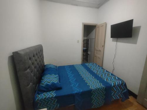 a bedroom with a bed with a blue comforter and a television at Acogedor apartamento en Buga in Buga