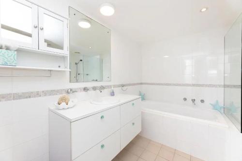 een witte badkamer met een wastafel en een bad bij Beachside 2 in Tuncurry