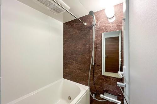 a bathroom with a tub and a shower with a mirror at aLATO Kinshicho in Tokyo