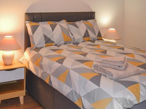 a bedroom with a colorful bed with two lamps at Harbour Apartment in Nairn