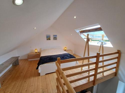 um quarto no sótão com uma cama e uma escada em Comfortable cottage close to the beach, Portsall, 2 canoes em Ploudalmézeau