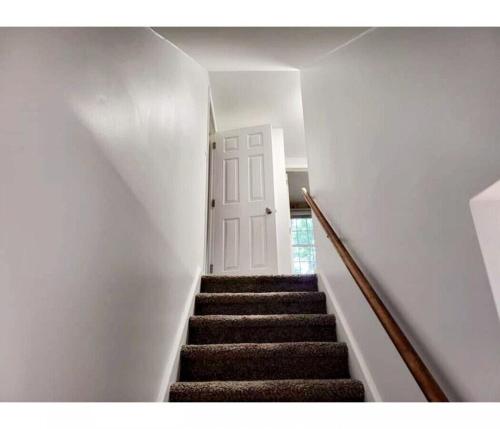 a staircase in a home with a white door and a stair case at 4-Bedroom House Close to Beach in Salisbury
