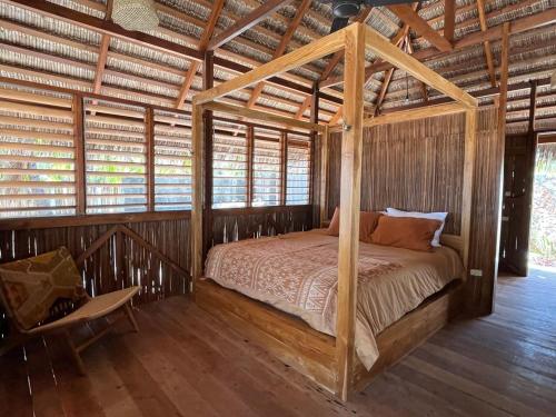 a bedroom with a canopy bed in a wooden house at VILLA LANGIT TEDUH ROTE in Nembrala