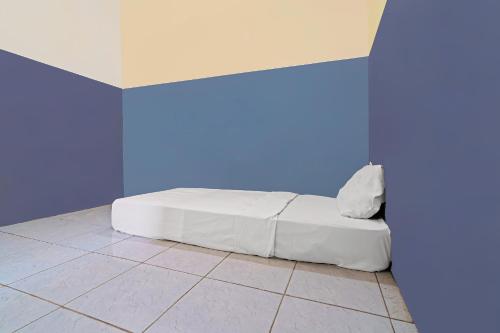 een wit bed in een kamer met een blauwe muur bij OYO 92893 Santana Residence Syariah in Bojongsalam