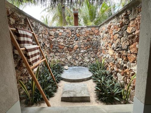 a patio with a chair and a stone wall at VILLA LANGIT TEDUH ROTE in Nembrala
