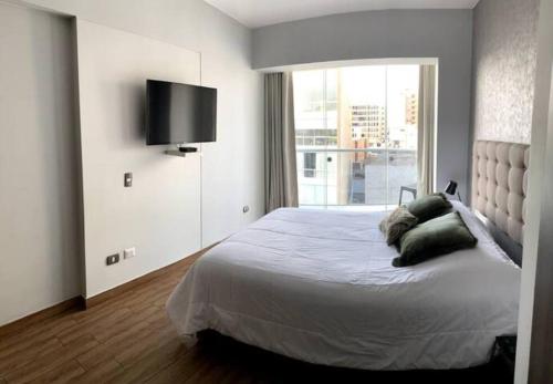 een slaapkamer met een bed en een televisie aan de muur bij MLA apartments - Larcomar in Lima