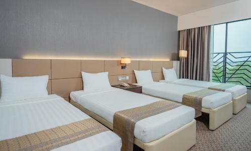 a hotel room with three beds and a window at Raia Hotel & Convention Centre Alor Setar in Alor Setar