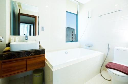 a white bathroom with a sink and a mirror at Avatar Danang Hotel in Da Nang