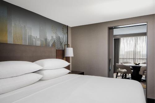 a bedroom with a large white bed and a table at Dallas-Addison Marriott Quorum by the Galleria in Addison