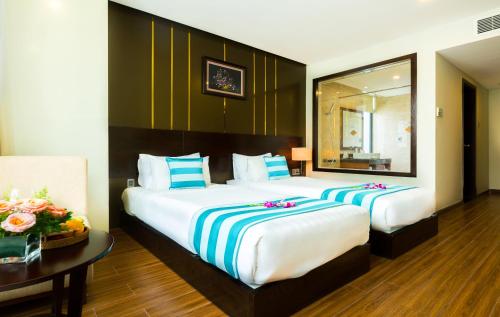 a bedroom with two beds and a table and a mirror at Avatar Danang Hotel in Da Nang