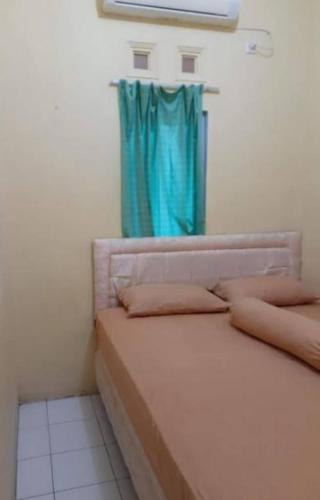 a bedroom with a bed with a blue curtain at Hotel prima in Benuaanyar