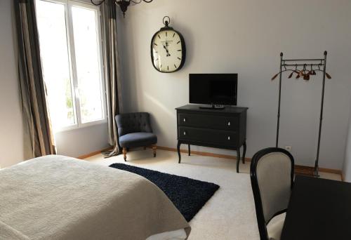 1 dormitorio con 1 cama y reloj en la pared en La Maison d'Hotes de Saint Leger, en Saint-Léger-en-Yvelines