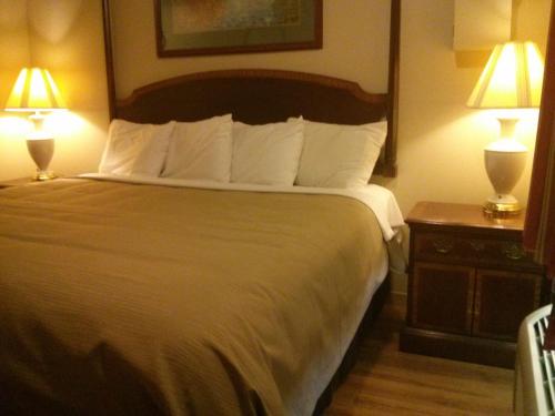 a hotel room with a large bed with two lamps at Port Motel in Port Colborne