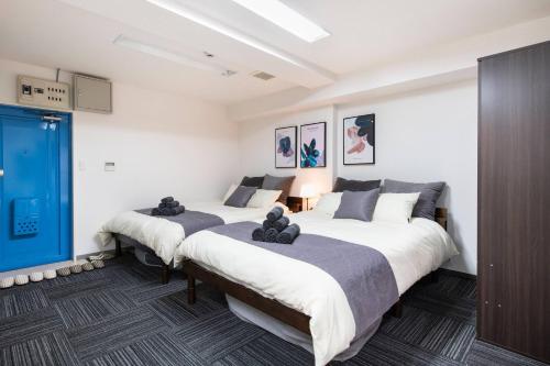 two beds in a room with white walls at Tsukimura Building in Tokyo
