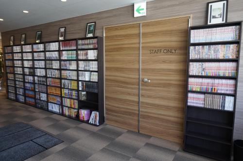 a library with a wooden door and shelves of books at Tabist Hotel Smart Sleeps Oita Station in Oita