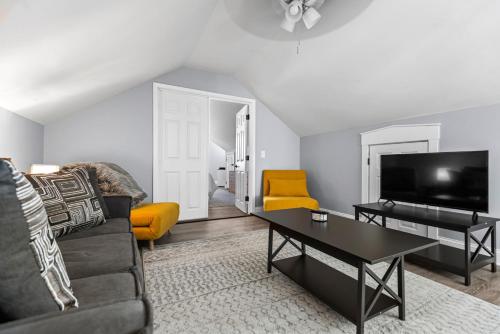 a living room with a couch and a tv at Main Street Balcony Apartment For up to 8 guests! in St. Charles
