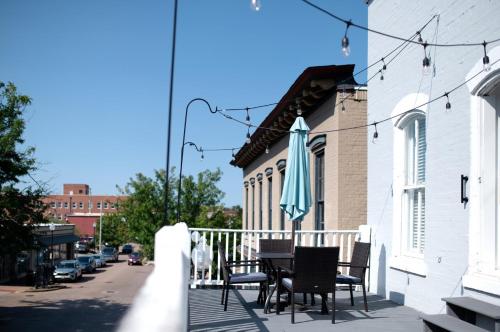 a patio with chairs and an umbrella on a building at Main Street Balcony Apartment For up to 8 guests! in St. Charles