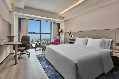 una camera d'albergo con un grande letto bianco e una scrivania di Crowne Plaza Beijing International Airport, an IHG Hotel a Shunyi