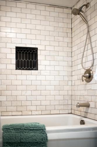 a white tiled bathroom with a tub and a shower at Private Basement Retreat in St. Charles
