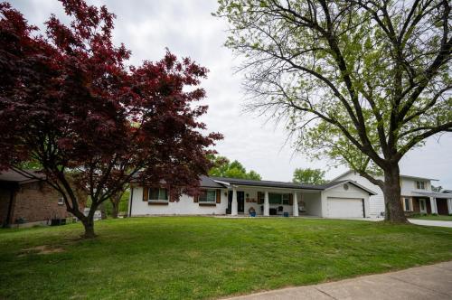 a white house with two trees in the yard at Private Basement Retreat in St. Charles